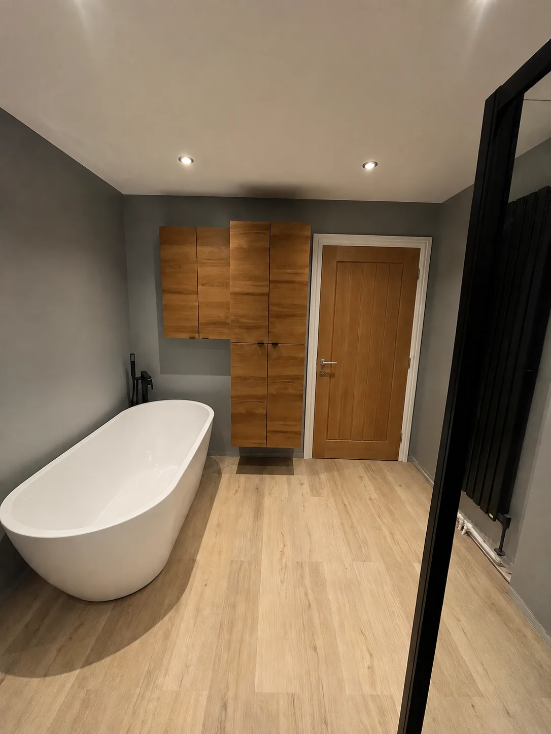 Main bathroom — freestanding tub, oak storage and oak finish door.